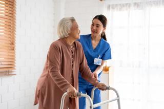 Elderly women walking assisted by a walker and nurse